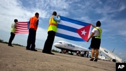 2016年8月31日在古巴的圣克拉拉机场跑道上，机场人员手持美国和古巴国旗迎接捷蓝航空387班机的到来。那架飞机是美古50多年来第一架商业航班。