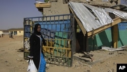 An unidentified woman walks past the ruins of a market outside the state police headquarters in Kano, Nigeria. Police said that members of the radical Islamist group Boko Haram dressed in uniforms resembling those of soldiers and police officers when they