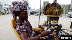 FILE - A woman selling plantain along a road counts the Nigerian naira near a currency exchange market in Ikeja district in Lagos, Nigeria, Aug. 12, 2017. 