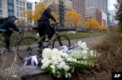 A bicyclist passes bouquets of flowers left by Argentine President Mauricio Macri and New York Mayor Bill de Blasio at the site of the terrorist attack, Nov. 6, 2017, in New York. Five Argentine bicyclists were among eight people killed by the terrorist,