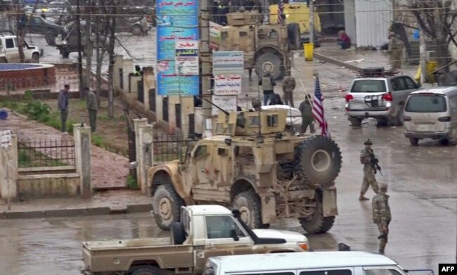 An image grab taken from a video obtained by AFPTV, Jan. 16, 2019, shows U.S. troops gathered at the scene of a suicide attack in the northern Syrian town of Manbij.