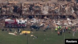Police and rescue workers stand near a building which was left destroyed from a massive explosion at a nearby fertilizer plant in the town of West, near Waco, Texas April 18, 2013.