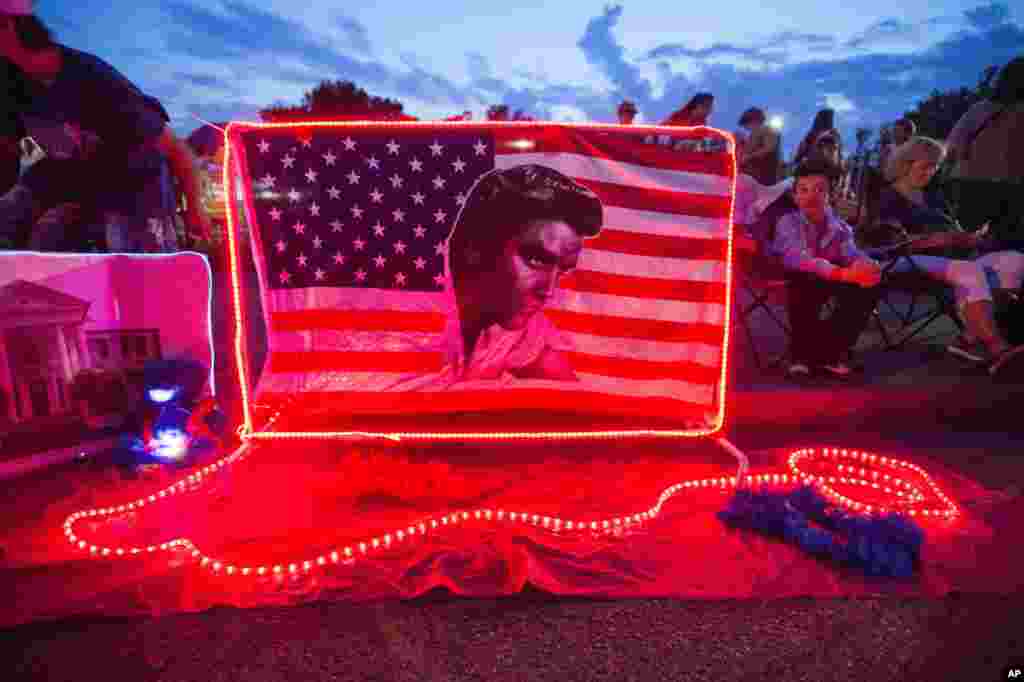 A street memorial is lit during a candlelight vigil for Elvis Presley in front of Graceland, Presley's Memphis home.