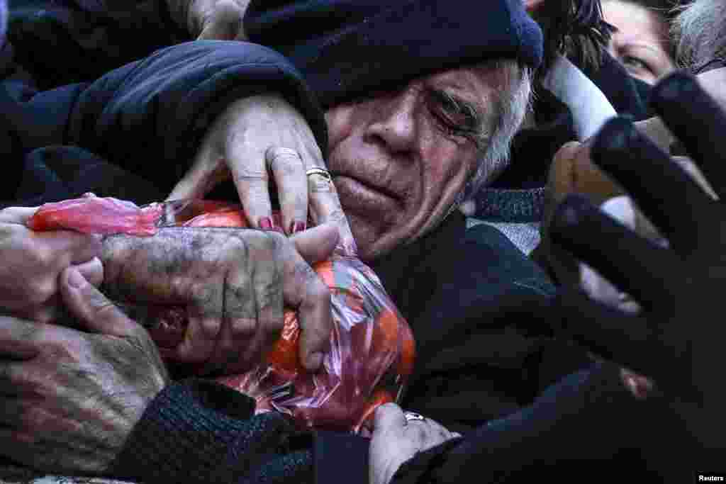 A man grasps a bag of tangerines as people receive free produce, handed out by farmers, during a protest over the government&#39;s proposal to overhaul the country&#39;s ailing pension system in Athens, Greece.