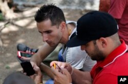 FILE - Internet users go online with their smartphones using the first public Wi-Fi hotspot in Havana, Cuba, July 2, 2015.