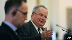 Greek Foreign Minister Nikos Kotzias, right, answers questions next to his German counterpart Heiko Maas during a joint press conference after their meeting in Athens, Greece, Sept. 20, 2018.