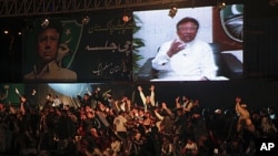 Leaders and supporters of the political party All Pakistan Muslim League surround a screen broadcasting a speech by their party president Pervez Musharraf from Dubai via video link, in Karachi, January 8, 2012.
