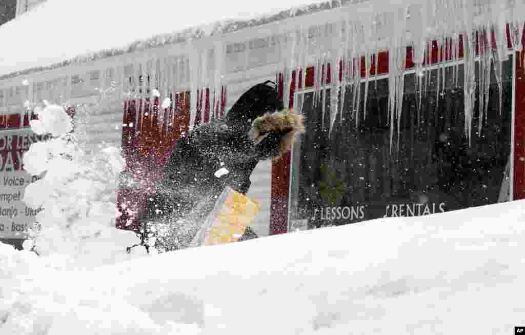 Corbit Larson clears snow in front of his Centre Music store in Framingham, Massachusetts. A long duration winter storm that began on Feb. 7 night remains in effect for a large swath of southern New England until the early morning hours on Feb. 10, 2015.