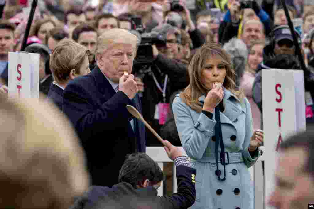 Presiden Donald Trump dan Ibu Negara Melania Trump meniup peluit tanda dimulainya lomba Balap Telur Paskah Gedung Putih, 2 April 2018.