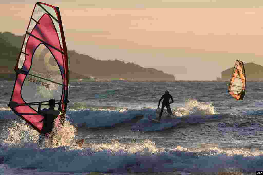 Surfers and windsurfers ride the waves of the Mediterranean Sea in Marseille.