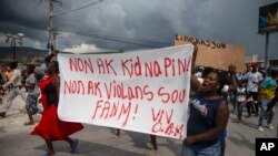 FILE - People carry a banner with a message that reads in Creole: 'No to kidnappings, no to violence against women ! Long live Christian Aid Ministries,' in Titanyen, north of Port-au-Prince, Haiti, Oct. 19, 2021.