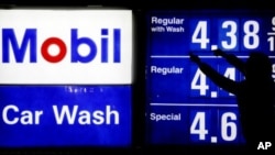 A gas station attendant raises gas prices on a display at Mobil gas station in Chicago, April 6, 2012.