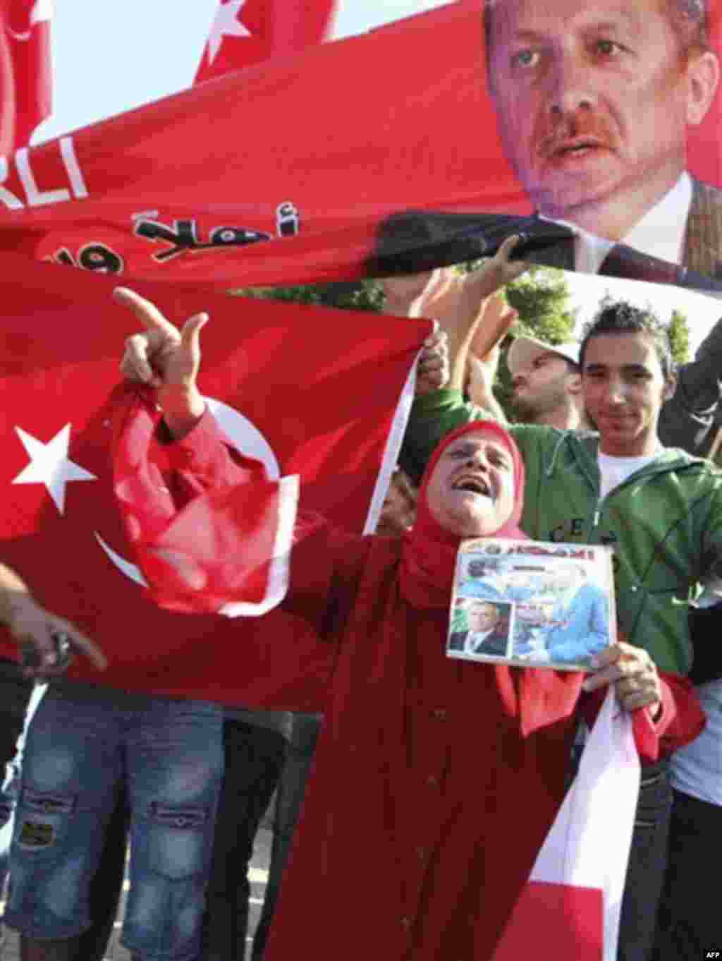 Supporters of Turkish Prime Minister Recep Tayyip Erdogan carry his pictures along Turkish flags as they gather outside Beirut International airport upon Erdogan's arrival in Lebanon, Wednesday, Nov. 24, 2010. (AP Photo/Bilal Hussein)