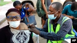 FILE - A woman receives a coronavirus vaccine in Abuja, Nigeria, Nov 29, 2021. 