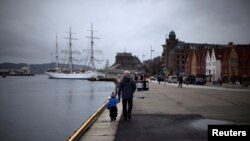 FILE - A man walks with a child near the marina in downtown Bergen, southwestern Norway, March 20, 2012. 