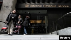 FILE - Women walk out of an Internal Revenue Service office in New York. 