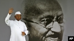 India's anti-corruption activist Anna Hazare waves next to a giant portrait of Mahatma Gandhi on the stage during his hunger strike in New Delhi,India, August 20, 2011