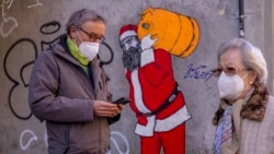 A man and woman wearing FFP2 masks to curb the spread of COVID-19 are seen in front of a mural depicting Santa Claus, in Madrid, Spain, Jan. 12, 2022.