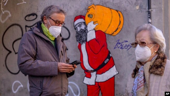 A man and woman wearing FFP2 masks to curb the spread of COVID-19 are seen in front of a mural depicting Santa Claus, in Madrid, Spain, Jan. 12, 2022.