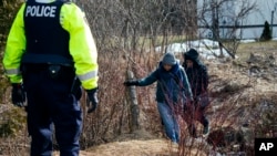Dos personas que dijeron a las autoridades ser sudanesas cruzan a Canadá desde Perry Mills, N.Y., cerca de Hemmingford, Quebec. Feb. 26, 2017.
