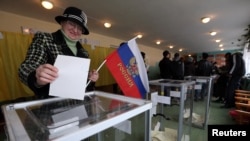 A woman holds a Russian flag as she casts her ballot during the referendum on the status of Ukraine's Crimea region at a polling station in Bakhchisaray March 16, 2014.