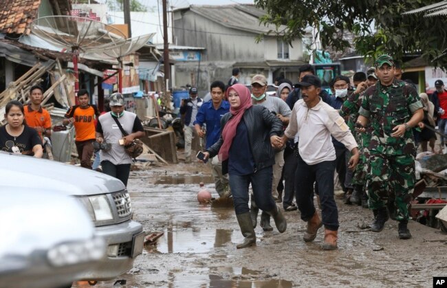 People feared by tsunami run in panic on a street in Sumur village, Indonesia, Dec. 25, 2018.