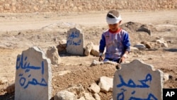 Ali Hamza, 8, at the graves of his brother, Mohammed, and sister, Asinat, who were killed at school by a nearby suicide car bombing, Qabak, Iraq, Oct. 7, 2013.