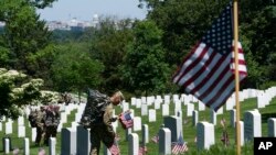 Miembros del Tercer Regimiento de Infantería del Ejército de Tierra, The Old Guard, colocan banderas estadounidense en el Cementerio Nacional de Arlington, el 24 de mayo de 2018.