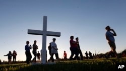 Attendees pass a wooden cross as they arrive at a candlelight vigil for the victims of the shooting at Marjory Stoneman Douglas High School in Parkland, Florida, Feb. 15, 2018. 