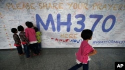 Anak-anak membaca pesan-pesan dan doa menyusul hilangnya pesawat MH 370 yang ditulis di tembok Bandara Internasional Kuala Lumpur, Malaysia, 13 Maret 2014 (Foto: dok). 