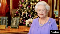 FILE - Britain's Queen Elizabeth poses for a photograph as she stands in the State Dining Room of Buckingham Palace, after recording her Christmas Day television broadcast to the Commonwealth, in London, Dec. 10, 2014. 