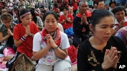 Thai 'Red Shirt' anti-government protesters pray during a ceremony to mark the 60th Coronation Day for King Bhumibol Adulyadej, inside their fortified camp in the financial central district of Silom in downtown Bangkok, 05 May 2010