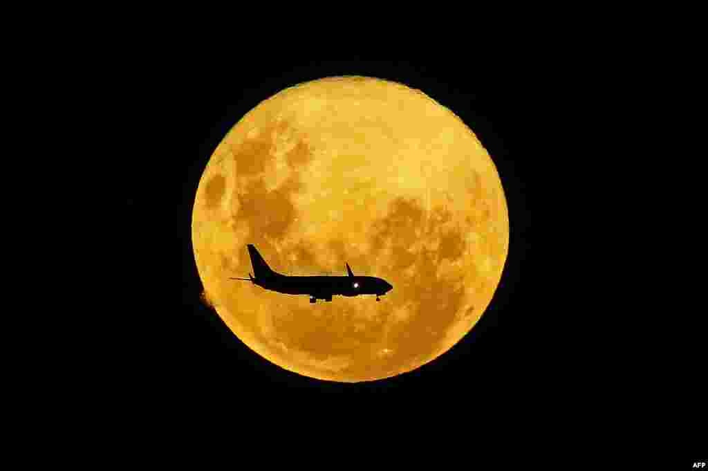 A plane passes in front of the full moon as seen from Curitiba, Brazil, March 9, 2020.