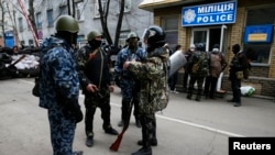 Pria-pria bersenjata di luar markas polisi di Slaviansk (12/4). Para militan pro-Rusia telah mengambil alih gedung kedua di kota Ukraina timur tersebut. (Reuters/Gleb Garanich)