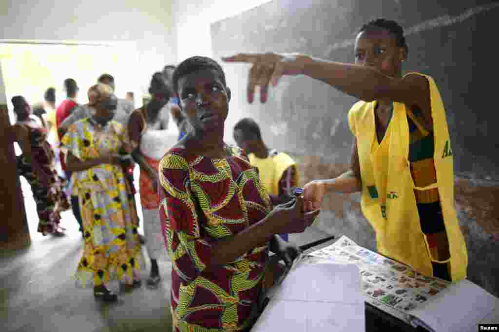 Un membre d'un bureau de vote de Cotonou, au Bénin, montre du doigt un isoloir, le 6 mars 2016. (REUTERS/Akintunde Akinleye)