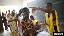 Un membre d'un bureau de vote de Cotonou, au Bénin, montre du doigt un isoloir, le 6 mars 2016. (REUTERS/Akintunde Akinleye)