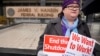 A U.S. Internal Revenue Services employee holds signs in front of the federal building at a rally against the U.S. federal government shutdown, in Ogden, Utah, Jan. 10, 2019.