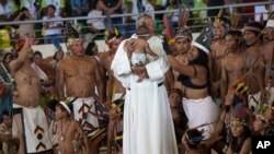 A priest holds a baby as clergy and indigenous people wait for the arrival of Pope Francis in Puerto Maldonado, Madre de Dios province, Peru.