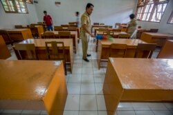 Anggota staf sekolah membersihkan ruang kelas setelah sekolah ditutup untuk mencegah penyebaran virus corona di Solo, Jawa Tengah, 16 Maret 2020. (Foto: AP)