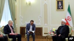 In this photo released by official website of the Office of the Iranian Presidency, Iranian President Hassan Rouhani, right, meets British Foreign Secretary Boris Johnson, left, at the presidency office in Tehran, Dec. 10, 2017. 