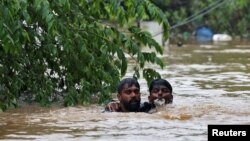 A man rescues a drowning man from a flooded area after the opening of Idamalayr, Cheruthoni and Mullaperiyar dam shutters following heavy rains, on the outskirts of Kochi, India, Aug. 16, 2018.