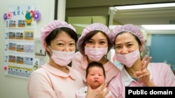 A group of nurses holds a newborn baby. The World Health Organization notes that, globally, there is a huge shortage of nurses and midwives.