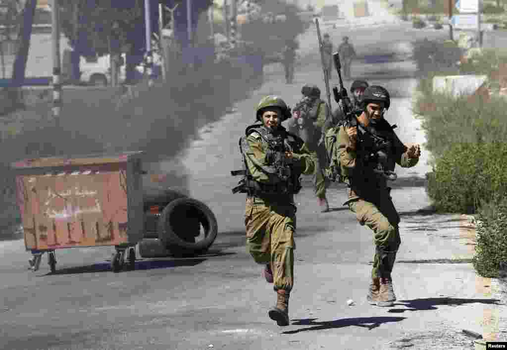 Israeli soldiers run during clashes with Palestinian protesters at a demonstration against the Israeli offensive in Gaza, near the Israeli settlement of Bet El, near Ramallah, July 25, 2014.&nbsp;