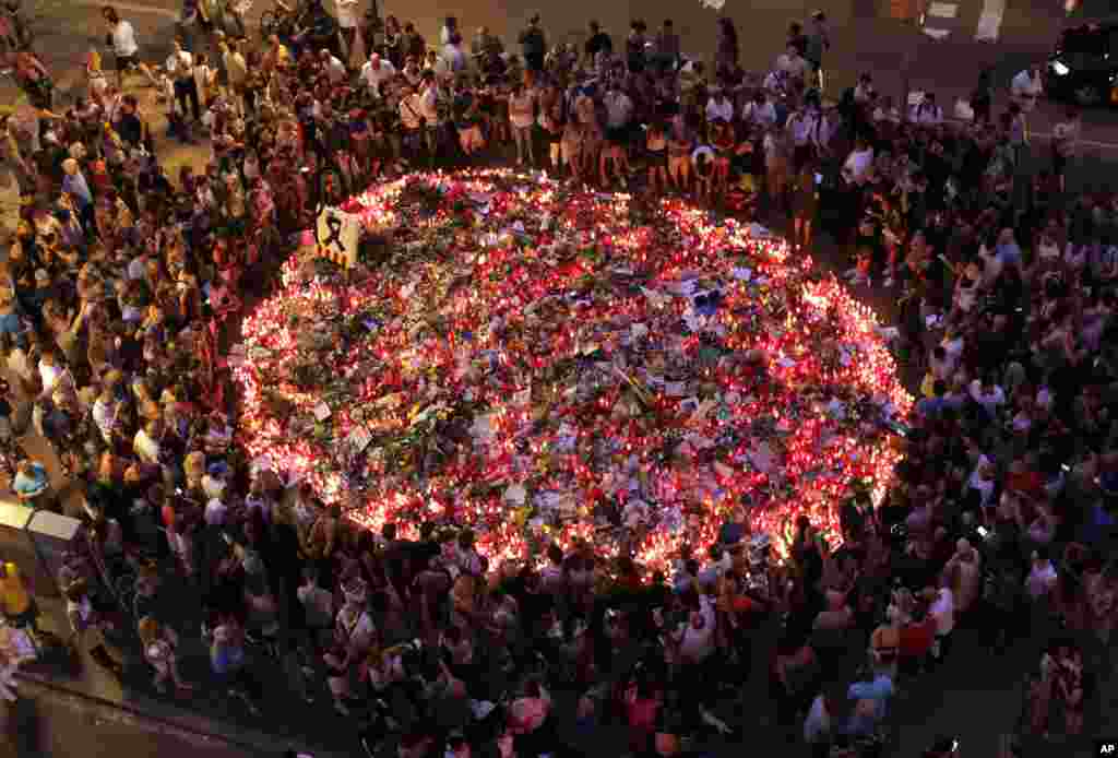 People pay respects at a memorial tribute of flowers, messages and candles to the victims on Barcelona&#39;s historic Las Ramblas promenade on the Joan Miro mosaic, embedded in the pavement where the van stopped after killing at least 14 people in Barcelona, Spain.
