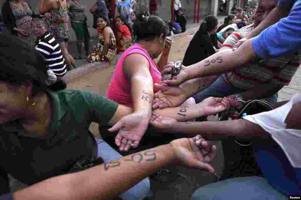 People show numbers written on their arms with the order they should enter at the state-run Bicentenario supermarket in Maracaibo. Lines are swelling at Venezuelan supermarkets, with some shoppers showing up before dawn in search of products ranging from chicken to laundry detergent, as a holiday slowdown in deliveries sharpened the nation&#39;s nagging product shortages.