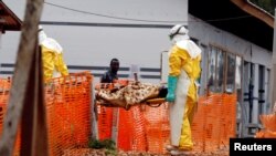 FILE - Health workers carry a newly admitted confirmed Ebola patient into a treatment center in Butembo in the eastern Democratic Republic of Congo, March 28, 2019.