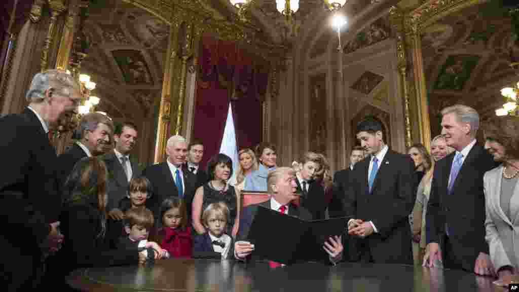 Le président Donald Trump, au centre, se tourne vers le président de la Chambre des représentants, Paul Ryan, entouré du vice-président Mike Pence et des membres de leurs familles, à l&#39;occasion de la signature officielle de la nomination de son cabinet, au Sénat, Washington, 20 janvier 2017.