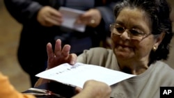 A woman receives her ballot in Portugal's general elections in Fontanelas, Sintra, outside Lisbon, Oct. 4, 2015.