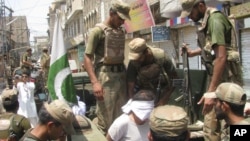 Pakistan army soldiers escort an alleged suspect arrested during a crackdown operation against militants in Bannu, Pakistan, July 16, 2012. 