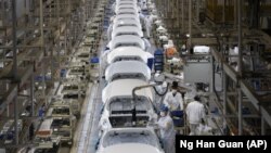 In this April 8, 2020, photo, employees work on a car assembly line at the Dongfeng Honda Automobile Co., Ltd factory in Wuhan in central China's Hubei province. (AP Photo/Ng Han Guan)